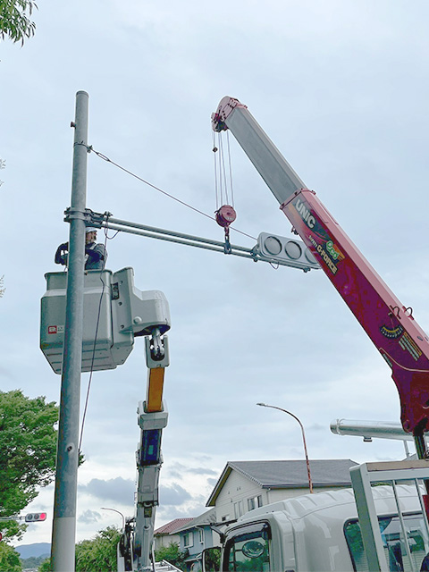 高所作業車のバケットに乗り、高い位置にある信号機の設置またはメンテナンス作業を行う作業員