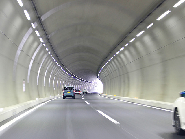 明るく照らされたトンネル内を走行する車の風景