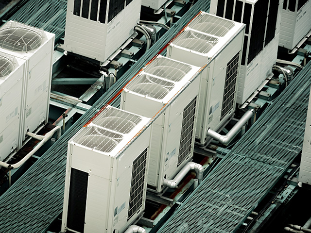 ビルの屋上に整然と並ぶ業務用エアコンの室外機群