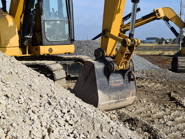 砂利や土を掘削する油圧ショベル（ユンボ）の力強い足元とバケットのアップ