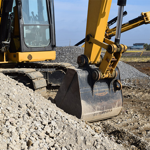 砂利や土を掘削する油圧ショベル（ユンボ）の力強い足元とバケットのアップ